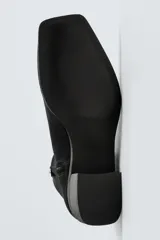 Botín de cuero negro con acabado serraje, cierre de cremallera lateral, horma cuadrada y tacón de 5 cm.