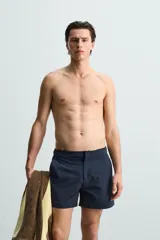 Short de baño celeste de tejido técnico con cintura elástica ajustable con cordón interior y trabillas laterales. Tiene bolsillos frontales y bolsillo trasero con cierre de cremallera. Cuenta con forro interior y cierre frontal con cremallera y botón a presión oculto.