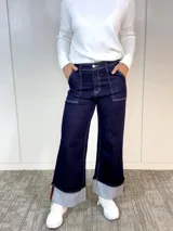 Pantalón de jean azul oscuro, de corte ancho, con bolsillos delanteros y traseros, y dobladillo ancho en el ruedo.