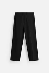 Pantalón gris de corte ancho con cintura elástica, pliegues frontales, bolsillos laterales y traseros de vivo. Incluye detalle de hebilla metálica en la trabilla y cierre frontal con cremallera y botón.