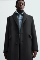 Abrigo negro regular fit confeccionado en paño con lana. Tiene cuello con solapas de muesca, manga larga, bolsillos de solapa en la cadera, bolsillo interior, abertura en el centro de la espalda y cierre frontal con botonadura.