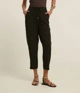 Pantalón fluido de cintura alta, confeccionado en crepé, con elástico y lazo en la cintura. Presenta un estampado geométrico con líneas curvas horizontales.