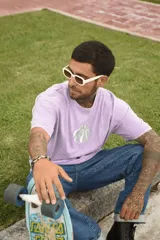 Remera color beige de algodón premium, manga corta y cuello redondo. Presenta un estampado circular en el centro del pecho con un diseño abstracto en tonos grises.