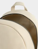 Mochila urbana negra de cuerina con bolsillo frontal con cierre y charm colgante de cadena con dije de corazón y candado. Tiene correas regulables, manija superior, cierre superior, doble bolsillo frontal (uno con charm metálico) y bolsillos laterales.