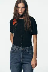 Pantalón de jean negro de corte recto, tiro alto y largo tobillero.