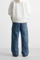 Pantalón de jean negro, corte relaxed fit, con bolsillos frontales y traseros tipo parche, tira multifunción y bolsillo tipo parche en las piernas. Tiene efecto lavado y cierre frontal con cremallera y botón.