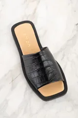 Sandalia abierta negra con textura de cuero de cocodrilo y suela plana.