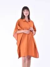 Vestido camisero color naranja de corte holgado, con cuello camisero, mangas cortas tipo kimono y cierre frontal con botones.