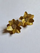 Par de aros dorados con forma de flor y centro brillante.