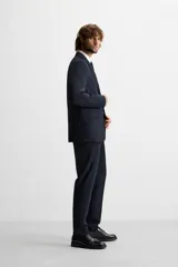 Pantalón de vestir azul marino, de corte slim fit, con bolsillos laterales y traseros de vivo con botón. Se ajusta a la cintura con cierre frontal con cremallera y botón.