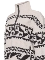 Buzo polar color crema con cuello alto, medio cierre y diseño étnico en negro.