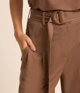 Pantalón de viscosa color verde esmeralda, modelo pantalón, cinturilla con trabilla y cinturón, cierre de cremallera y mosquetón. Pieza con detalles y bolsillo delantero.