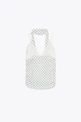 Top blanco con estampado de lunares negros, escote pico, tirantes finos y detalle de foulard en el mismo tejido.