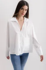 Camisa blanca de algodón con cuello clásico, mangas largas con puños abotonados y bolsillo de parche en el frente.