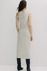 Vestido midi de punto elástico color beige, de corte entallado, con escote asimétrico, manga corta con detalle girado, y frunces laterales que crean un efecto drapeado.