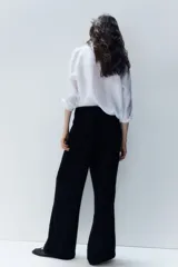 Pantalón negro de corte holgado en tejido de punto con textura. Modelo de tiro alto con cintura elástica y piernas rectas.