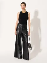 Pantalón de cuero vacuno negro, de silueta amplia con recortes diagonales en delantero y espalda. Tiene un complemento de lino al tono aplicado en los laterales.