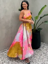 Vestido largo de tela fluida, color verde esmeralda con estampado abstracto en tonos turquesa y detalles dorados. Diseño asimétrico con un solo tirante tejido en el hombro.