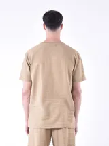 Remera blanca a rayas horizontales grises, con cuello redondo abotonado y bolsillo en el pecho.