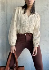 Camisa color manteca con bordado inglés, cuello en V y mangas largas abullonadas.