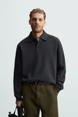 Polo manga larga negro de algodón con elasticidad y estructura. Cuello solapa con cierre frontal de botonadura y acabados con rib.