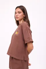 Remera color chocolate de corte holgado, con cuello redondo y mangas cortas con dobladillo. Estampado pequeño en el pecho con logo de frutas.