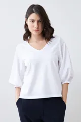 Remera blanca con escote en V y mangas balloon 3/4.