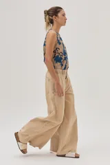 Pantalón jean de pierna ancha color beige, con cintura elastizada y bolsillos traseros cuadrados.