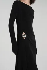 Vestido largo negro de jersey texturizado con spandex y acabado brillante, corte ajustado, escote redondo, manga larga, abertura lateral a la altura de la cadera con detalle metálico.