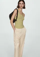 Pantalón color beige de tejido fluido, corte recto y diseño largo. Cuenta con cintura elástica, bolsillos laterales, bolsillos cargo y bolsillos de ribete en la parte posterior.