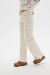 Pantalón jean negro de tiro alto, corte flare y detalle de tachas plateadas en los laterales.