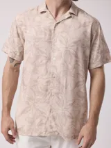 Camisa de hombre de manga corta con cuello cubano y estampado de hojas en tonos beige y blanco.