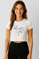 Remera blanca corta de algodón con cuello redondo y estampado de moños de colores.