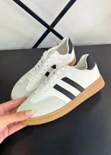 Championes blancos con detalles en negro, con tres tiras negras en el lateral y suela color caramelo.