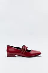 Zapato tipo Mary Jane color negro con textura de reptil, de charol sintético con punta cuadrada y triple tira con hebillas.