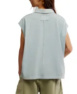 Remera estilo polo blanca de corte amplio con cuello clásico y botonadura corta en el frente. Tiene mangas cortas con dobladillo y aberturas laterales en el ruedo.