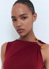 Vestido midi color borgoña, de corte ajustado, sin mangas y con detalle drapeado en el lateral. Presenta un adorno dorado en el hombro.