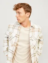 Sobrecamisa a cuadros color blanco, marrón y negro, de manga larga con cierre de botones y bolsillos en el pecho.