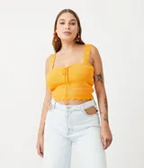 Blusa cropped de punto color amarillo, con tirantes anchos y escote con cordón.