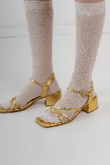 Sandalias doradas de cuero metalizado con tiras finas cruzadas, plantilla cuadrada y taco bajo de 4 cm.