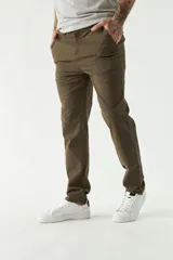 Pantalón chino color beige, de corte slim, con bolsillos laterales y traseros. Se ajusta a la cintura con cinturón de cuero marrón.