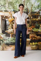 Pantalón de jean azul oscuro, de corte acampanado, con bolsillos delanteros con detalle de volados.