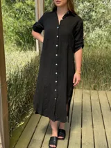 Vestido camisero largo negro de lino, con corte en la cintura, abertura lateral y botones de nácar.