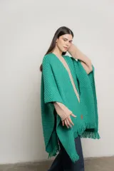 Ruana verde esmeralda de tejido de punto con flecos en el borde inferior.