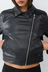 Campera biker negra de efecto cuero, con cierre delantero asimétrico, bolsillos laterales con cierre y cuello con solapa adornado con tachas.