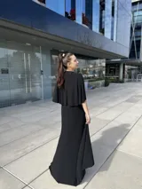 Vestido negro largo con escote en V, mangas cortas tipo kimono, falda cruzada con abertura y cinturón fino con strass.