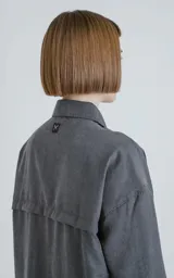 Camisa manga larga color gris grafito, estilo técnica con múltiples bolsillos delanteros y un bolsillo en la parte inferior de la espalda. Tiene botones en la cartera y las mangas, y calce oversize.