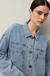Sobrecamisa de jean celeste con cuello camisero, cierre con botones metálicos, bolsillos frontales con solapa y corte oversize.