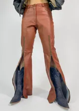 Pantalón de cuero color marrón, de corte recto, tiro medio alto y cierre en los tobillos.