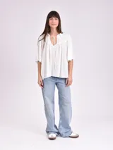 Blusa blanca de mangas cortas con escote en V y lazos.